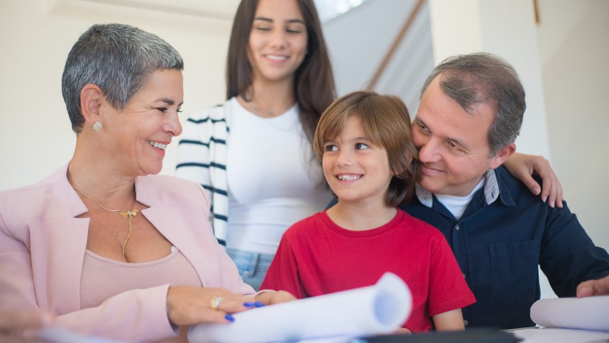Smiling family indoors signing real estate documents. Friendly interaction and teamwork.
