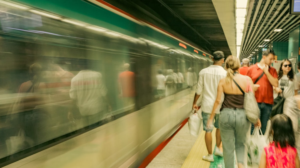 Commuters navigate a bustling subway platform as a train speeds by in İstanbul, Türkiye.